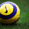 Close-up of a yellow and blue Nike soccer ball on a soccer field.